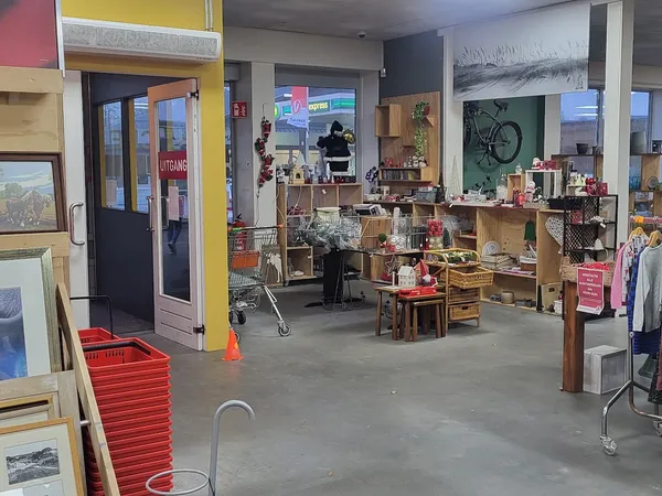 Winkelvloer van kringloopwinkel met houten stellingen, huisraad, kleding en diverse tweedehands spullen
