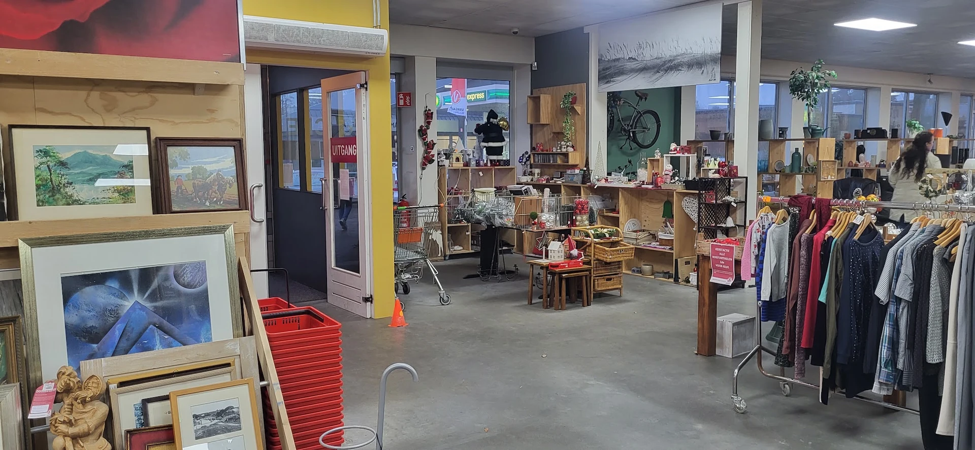 Winkelvloer van kringloopwinkel met houten stellingen, huisraad, kleding en diverse tweedehands spullen
