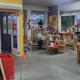 Winkelvloer van kringloopwinkel met houten stellingen, huisraad, kleding en diverse tweedehands spullen