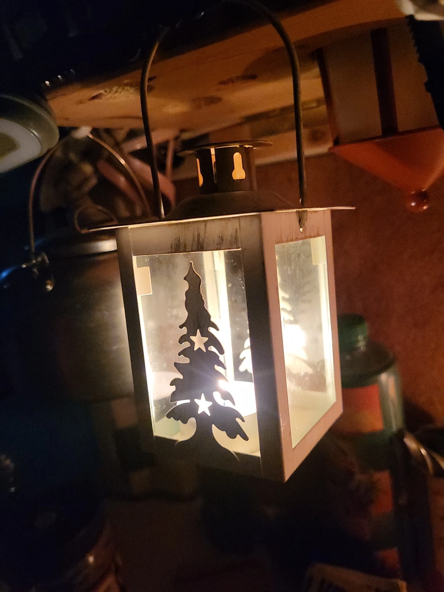 Verlichte decoratieve lantaarn met silhouet van een kerstboom en sterren