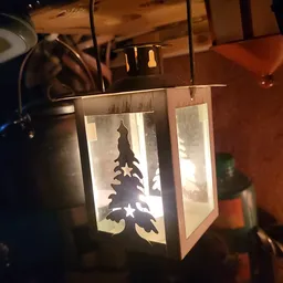 Verlichte decoratieve lantaarn met silhouet van een kerstboom en sterren