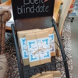Ingepakt cadeautje met blauwe decoratieve verpakking en handgeschreven labels in een winkelrekje