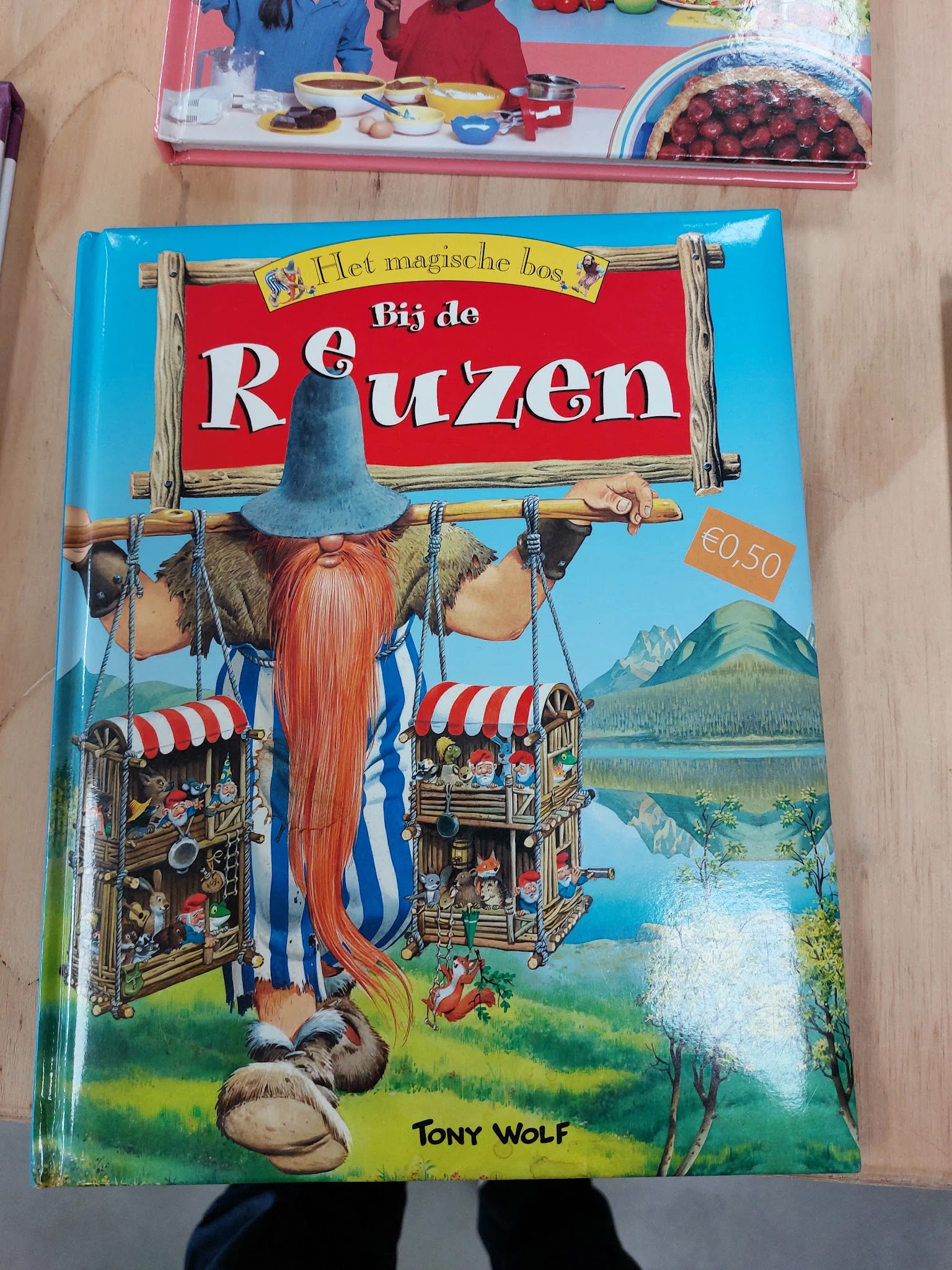 Kinderboek 'Bij de Reuzen' met illustratie van een reus met rode baard en blauwe hoed