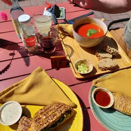 Lunch op een terras met soep, brood en dranken op een roze tafel