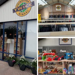 Overzicht van kringloopwinkel met kleding op hangers, speelgoed en huishoudelijke artikelen op schappen en tafels