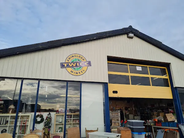 Voorgevel van kringloopwinkel Twice met logo, blauwe kozijnen en gele laaddeuren