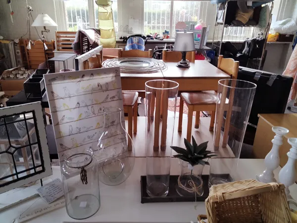 Tafel met huishoudelijke artikelen en decoratie, waaronder glazen, een plant in pot en een mand