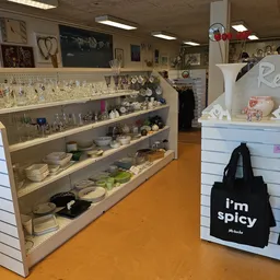 Glazen stellingen vol serviesgoed, glazen, kannen en huishoudelijke artikelen in een kringloopwinkel
