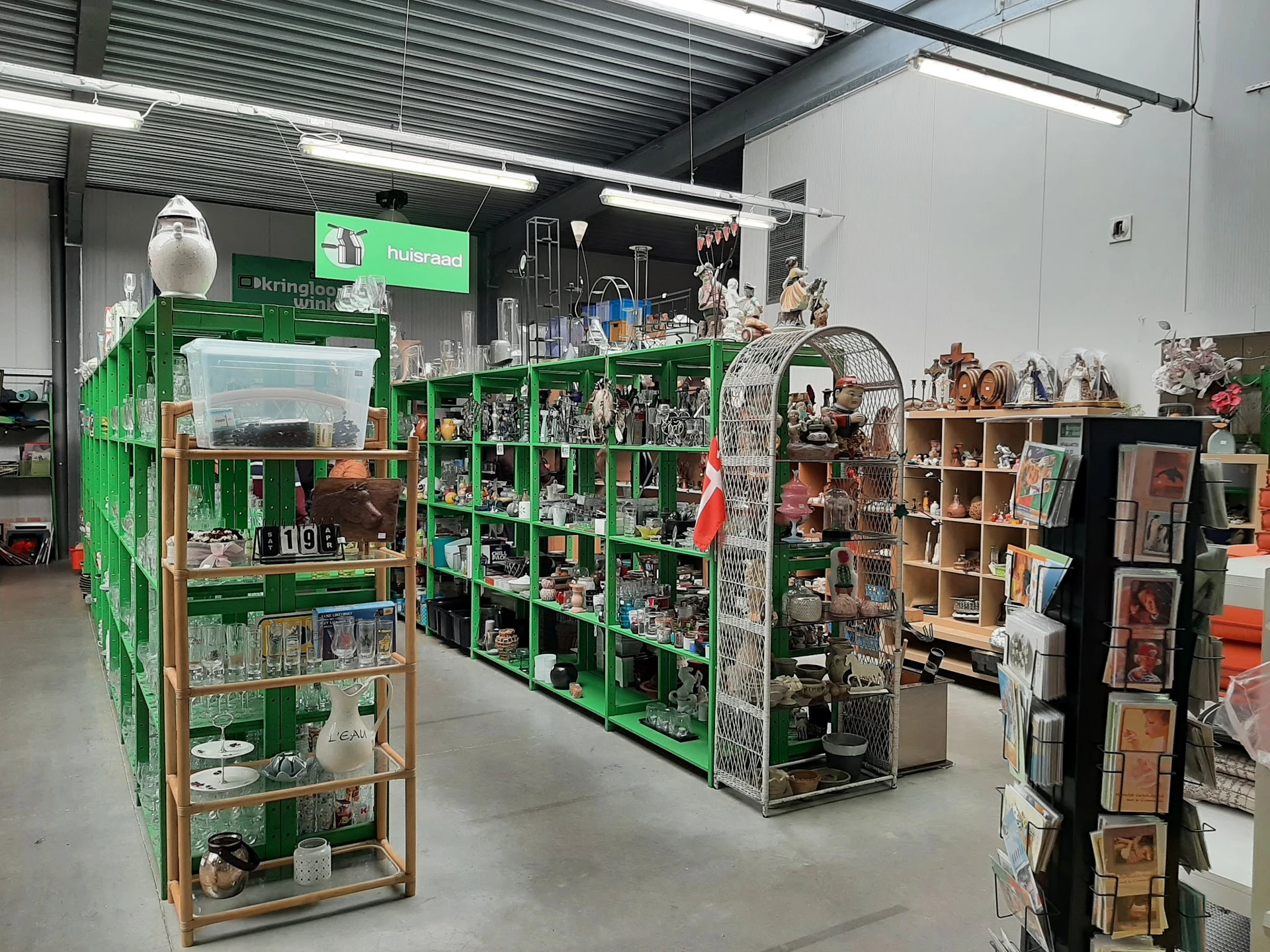 Winkelvloer met groene stellingen vol decoratieartikelen, beeldjes en huishoudspullen