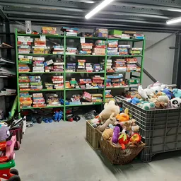 Winkelvloer met groene stellingen vol speelgoed en dozen, kinderspeelgoed in foreground
