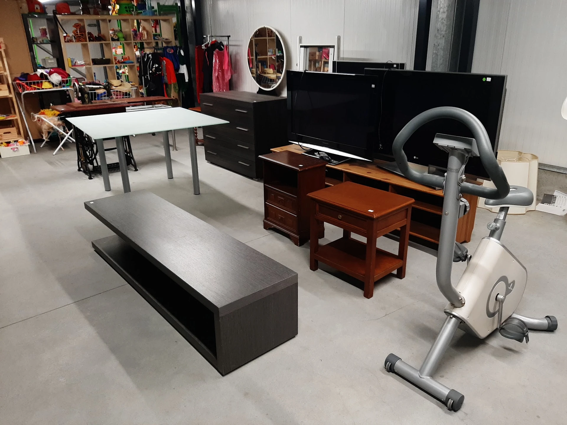 Winkelvloer met diverse meubels: tafels, kasten, bankje en hometrainer