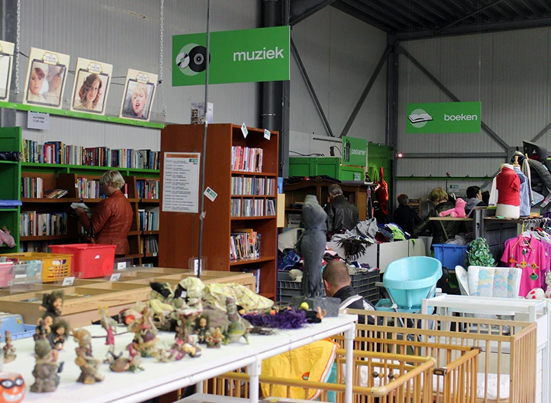 Ruime winkelvloer met boekenkasten, speelgoed, kleding en diverse tweede-handsspullen uitgestald