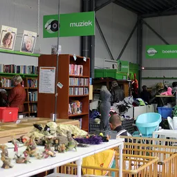 Ruime winkelvloer met boekenkasten, speelgoed, kleding en diverse tweede-handsspullen uitgestald