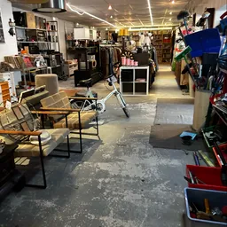 Binnenaanzicht van kringloopwinkel met verschillende meubels, fietsen, stellingen met spullen en winkelafdelingen