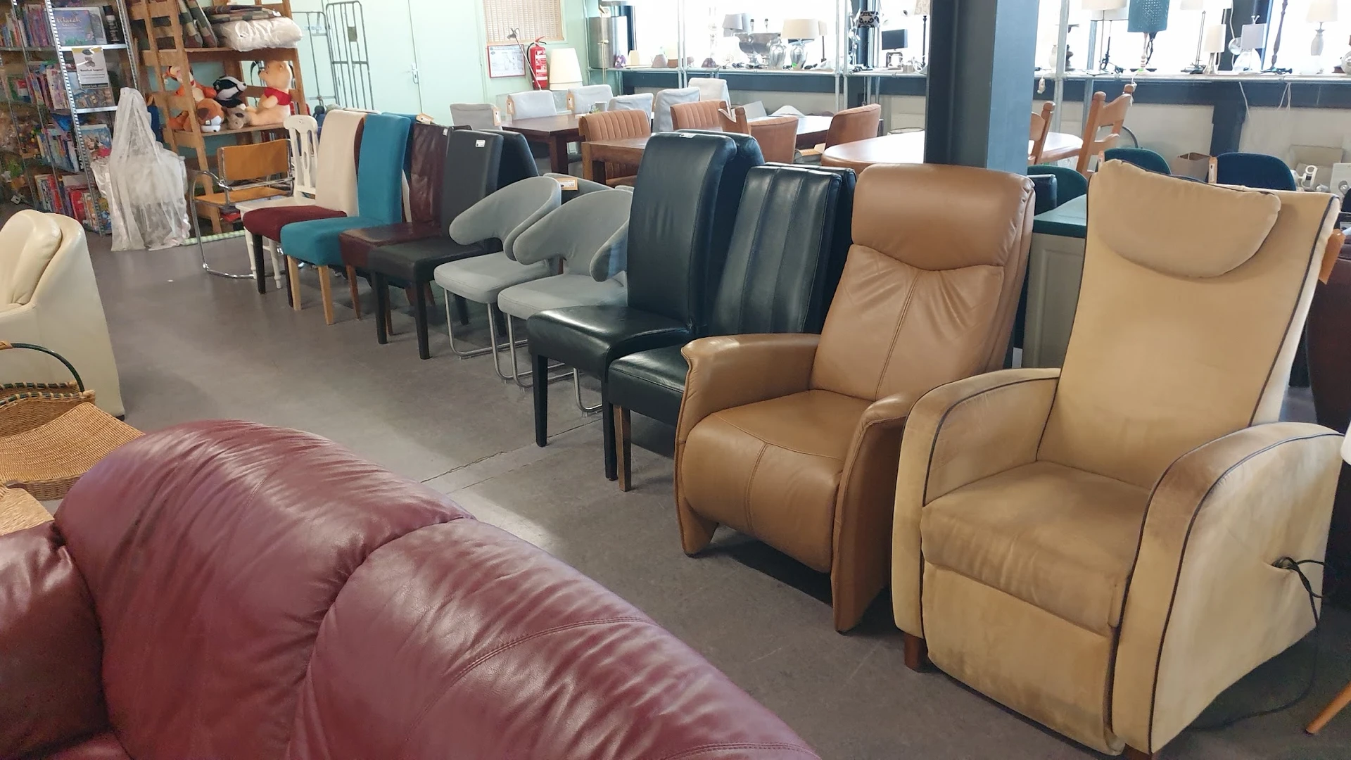 Diverse tweedehands stoelen en fauteuils in verschillende kleuren en stijlen, uitgestald in de winkel