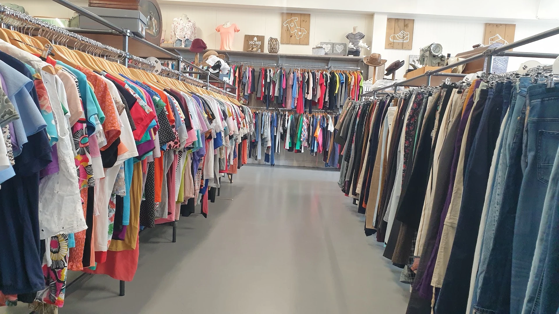 Rekken met tweedehands kleding in verschillende kleuren en stijlen in de winkel