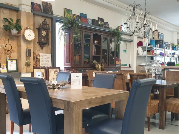 Winkelbinnenruimte met houten eettafel, blauwe stoelen en vintage meubels tegen de wand