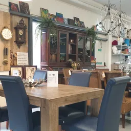 Winkelbinnenruimte met houten eettafel, blauwe stoelen en vintage meubels tegen de wand