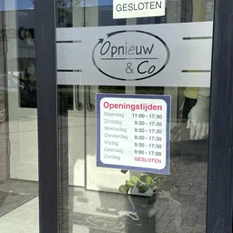Openingstijdenbord op winkelruit met naam en maandagslot