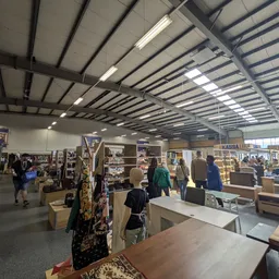 Winkelvloer van kringloopwinkel met stellingen, rekken met spullen en bezoekers die rondlopen