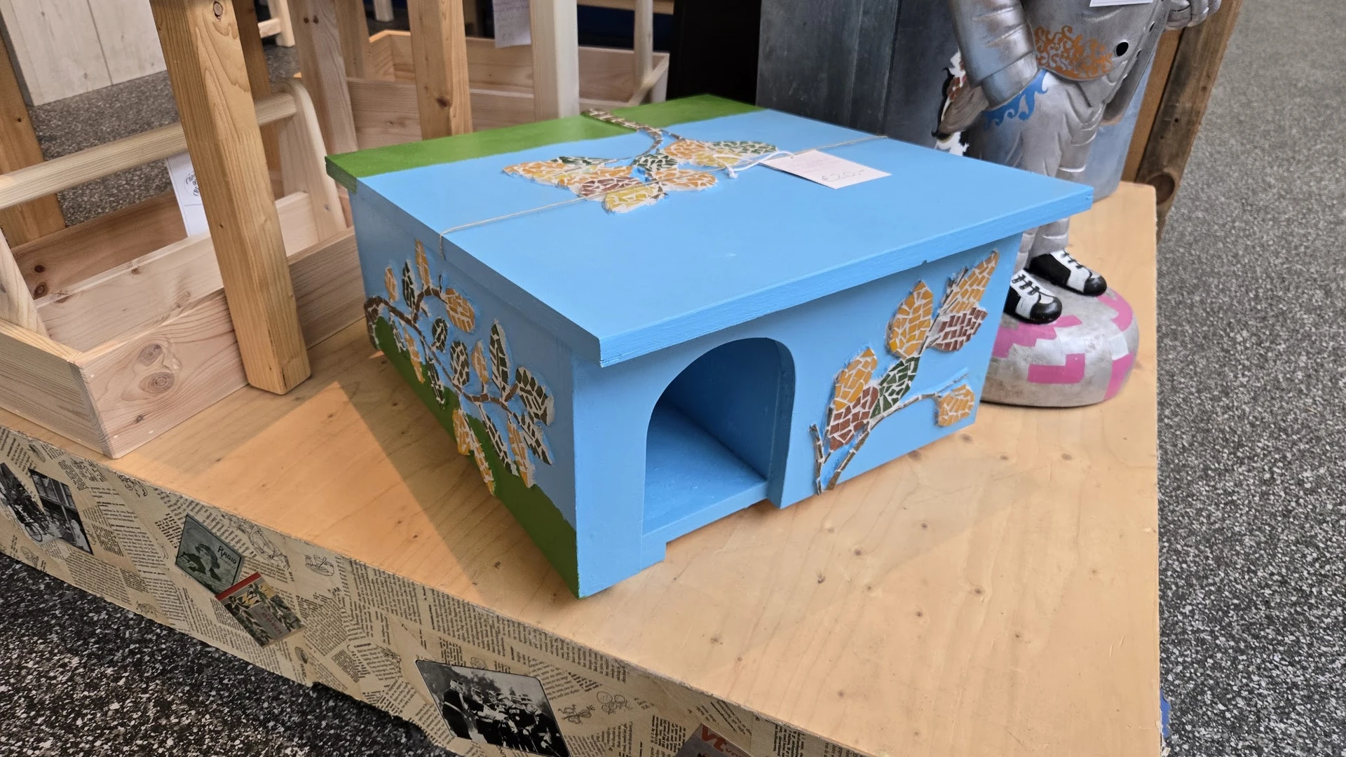 Blauwe houten kattenhuisje met goudkleurige decoratieve details op het dak