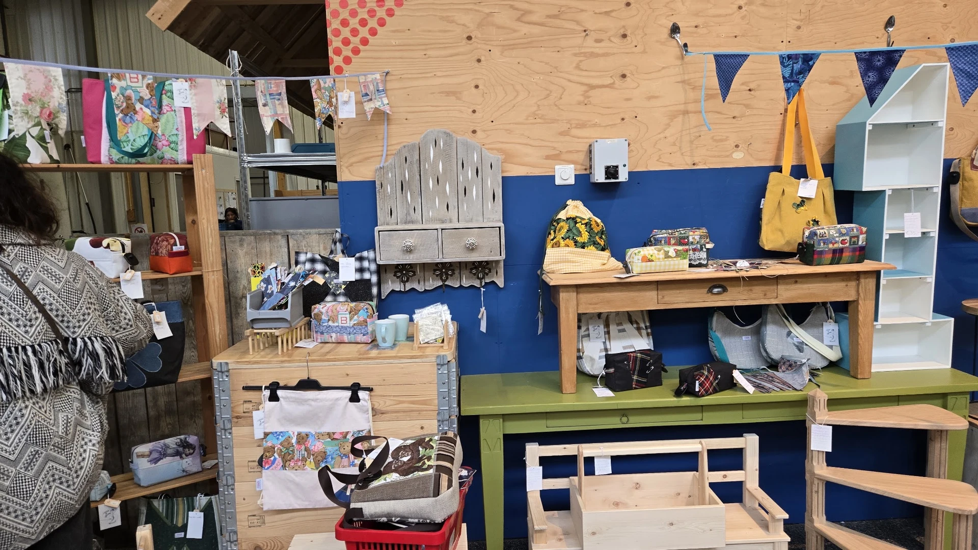 Werkruimte met houten werkbank, blauwe muur, gereedschap, muziekinstrumenten en diverse spullen op planken