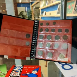 Spiraalalbum met rode kunststof munthouders gevuld met munten uit verschillende landen