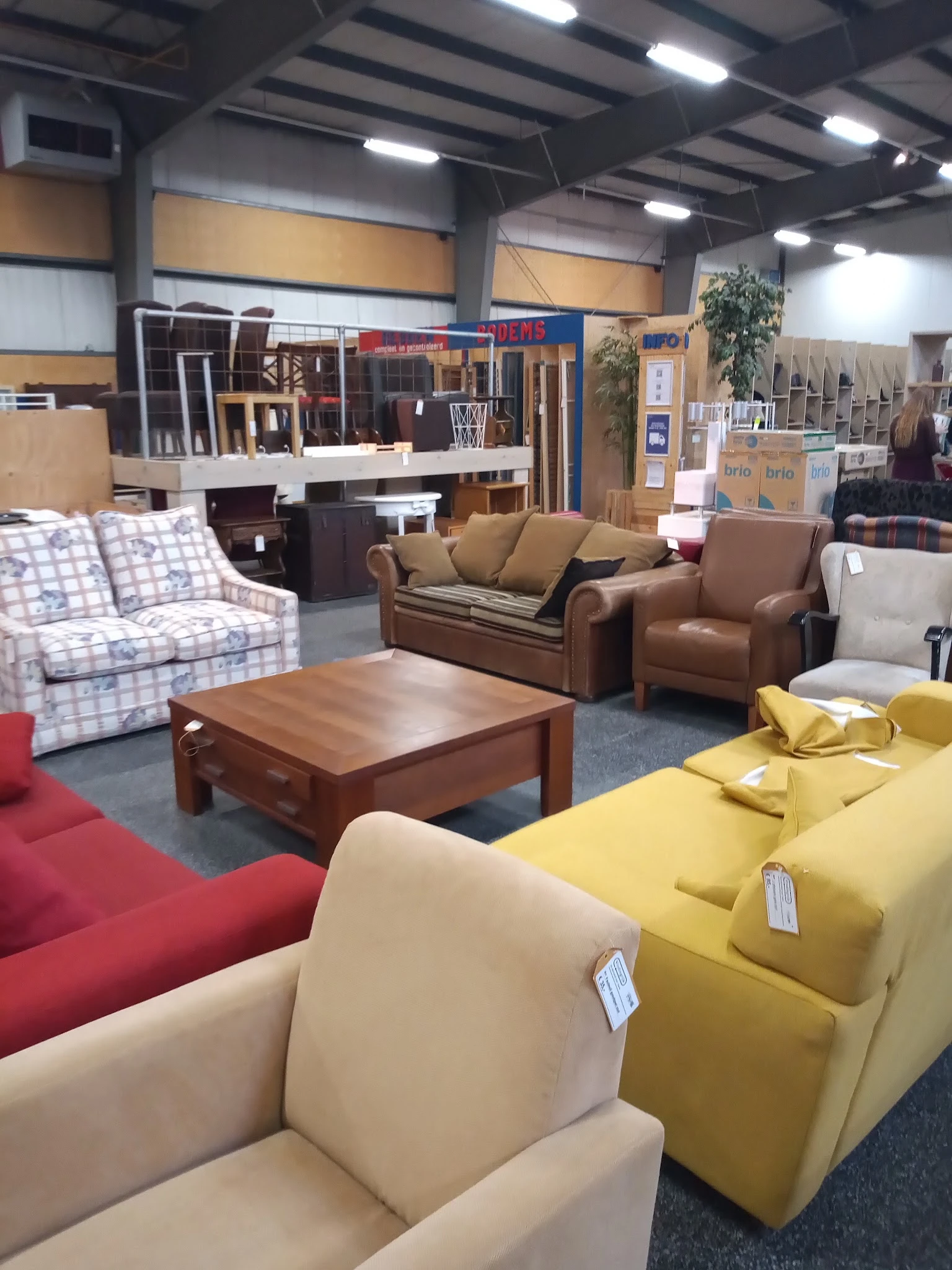 Tweedehands meubels in de winkel: banken, fauteuils, stoelen en een houten salontafel