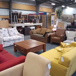 Tweedehands meubels in de winkel: banken, fauteuils, stoelen en een houten salontafel
