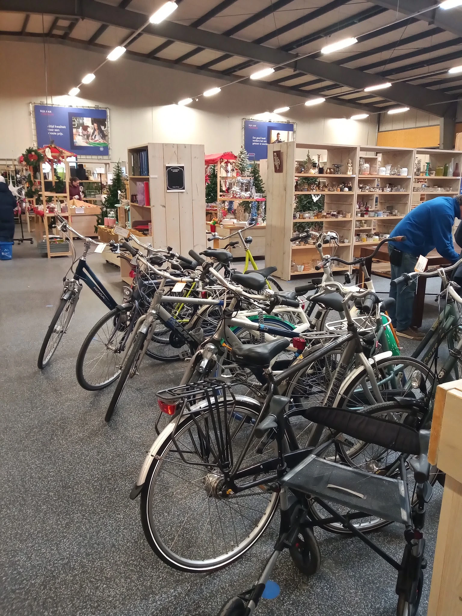 Meerdere tweedehands fietsen uitgestald in de winkel met op de achtergrond kasten en kerstdecoratie