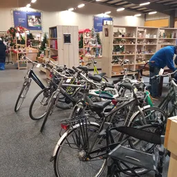 Meerdere tweedehands fietsen uitgestald in de winkel met op de achtergrond kasten en kerstdecoratie