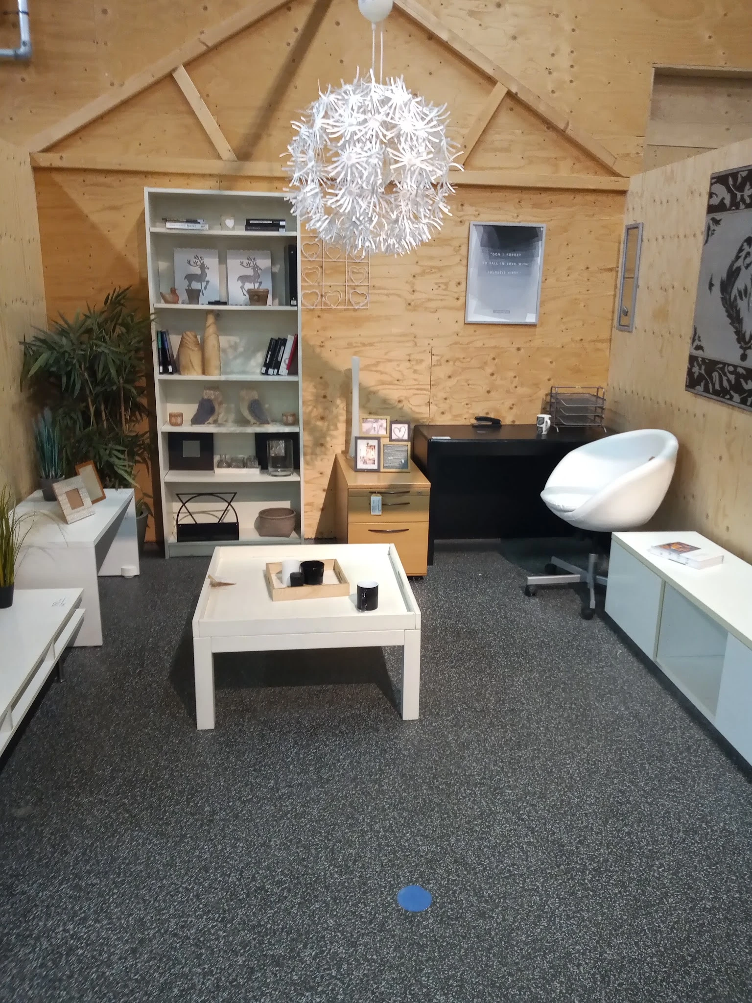 Winkelvloer met uitgestalde meubels en decoratieartikelen, waaronder een witte salontafel, zwarte piano, wit stoeltje en open