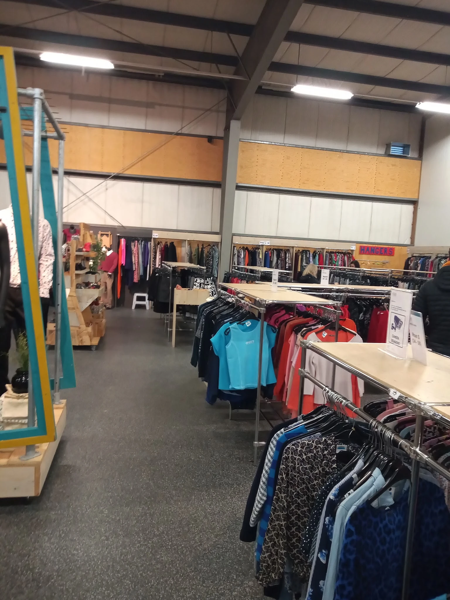 Winkelvloer met kledingrekken en uitgestalde tweedehands kleding in verschillende kleuren