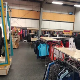 Winkelvloer met kledingrekken en uitgestalde tweedehands kleding in verschillende kleuren