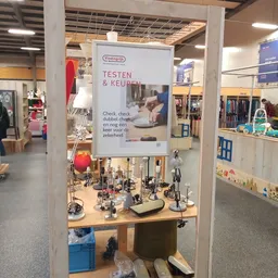 Informatief bord met 'Testen & Keupen' en displayfiguren onder het bord