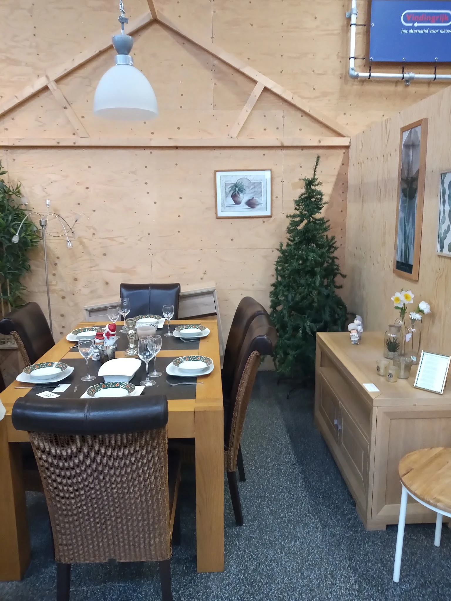 Ingerichte eethoek met houten tafel, zwarte stoelen, gedekt voor maaltijd, decoratie met plant en bloemen