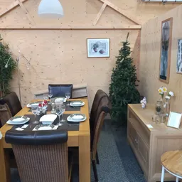 Ingerichte eethoek met houten tafel, zwarte stoelen, gedekt voor maaltijd, decoratie met plant en bloemen