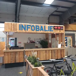 Houten gevel van kringloopwinkel met blauwe INFOBALIE-letters en ingang