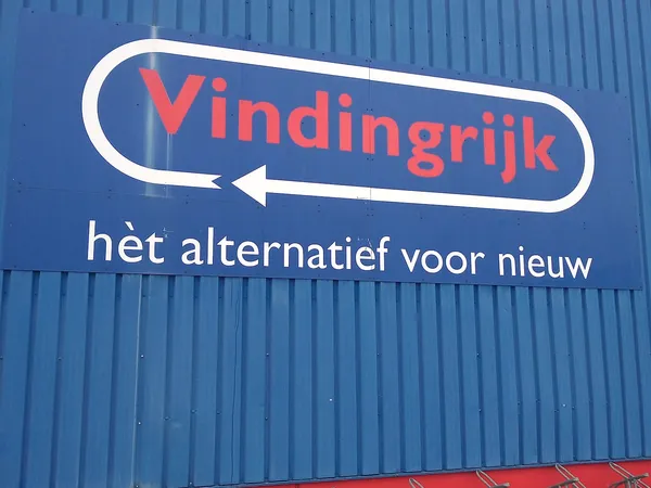 Blauwe gevel met wit en rood logo en pijl van kringloopwinkel Vindingrijk met tagline