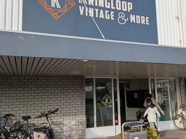 Voorkant van kringloopwinkel met blauwe gevel, winkelnaam Vintage & More, glazen deuren en ramen, fietsen ernaast