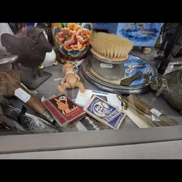 Vitrinekast met diverse vintage en antieke artikelen zoals borstels, decoratieve voorwerpen en blauwe aardewerk