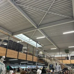 Metalen golfplaten plafond met balken, trap en reling in industrieel magazijnachtig ruimte