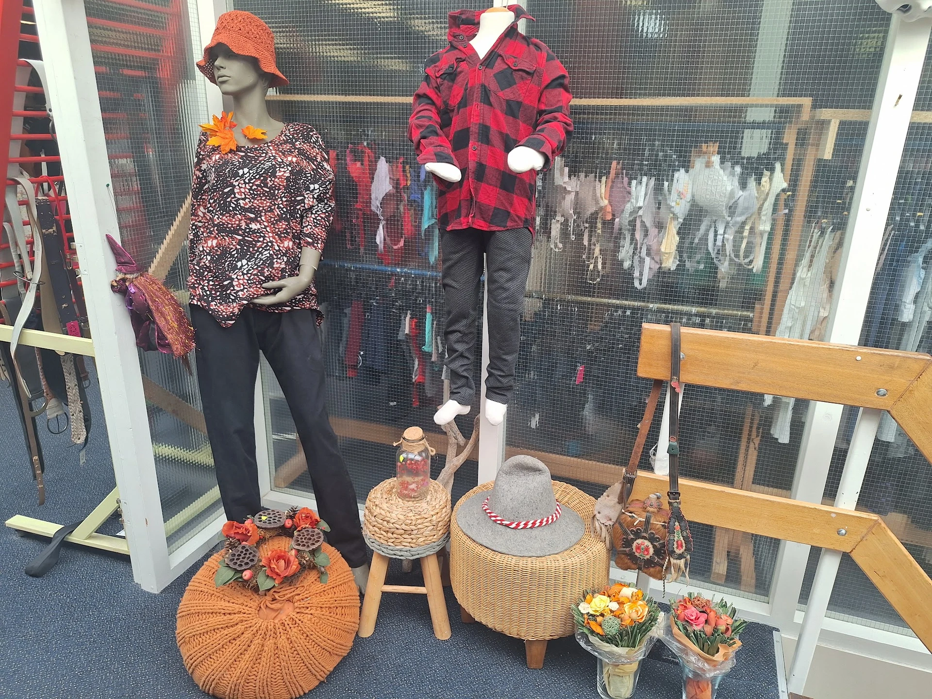 Etalage met mannequins in seizoenskleding en accessoires, inclusief petten, sjaals en decoratieve items
