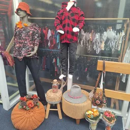 Etalage met mannequins in seizoenskleding en accessoires, inclusief petten, sjaals en decoratieve items