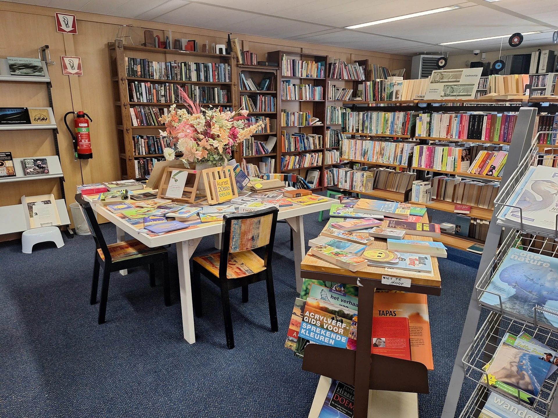 Boekenwinkel interieur met boekenrekken, leestafels met boeken en bloemen, sfeervolle werkplek