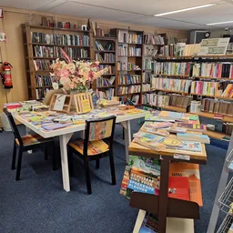 Boekenwinkel interieur met boekenrekken, leestafels met boeken en bloemen, sfeervolle werkplek