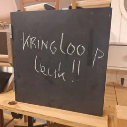 Zwart bord met witte handgeschreven tekst 'BRING LOO P (BUSH !!'