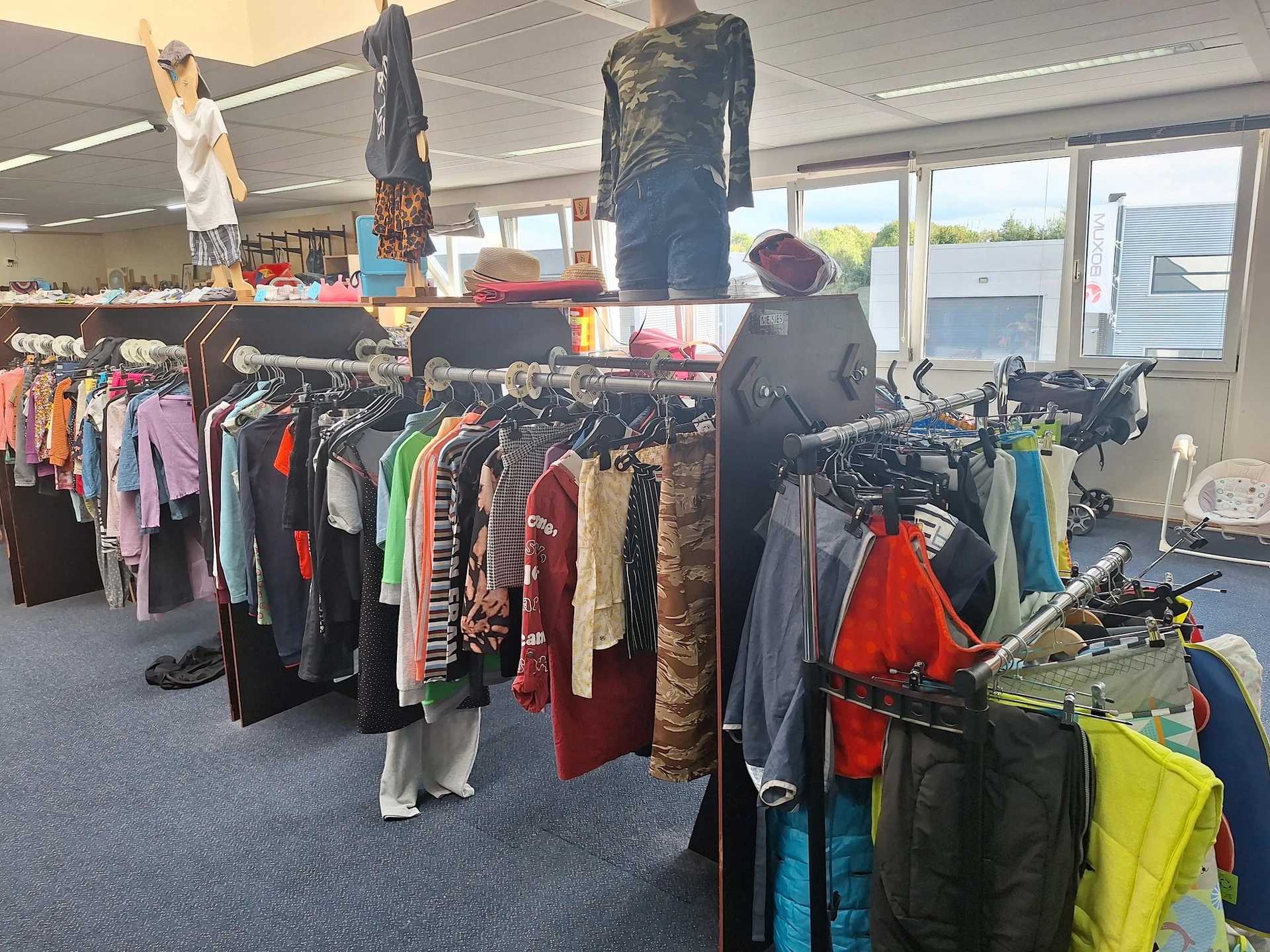 Kledingrekken met tweedehands kleding in verschillende kleuren en stijlen, met mannequins en opgehangen kledingstukken