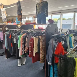 Kledingrekken met tweedehands kleding in verschillende kleuren en stijlen, met mannequins en opgehangen kledingstukken