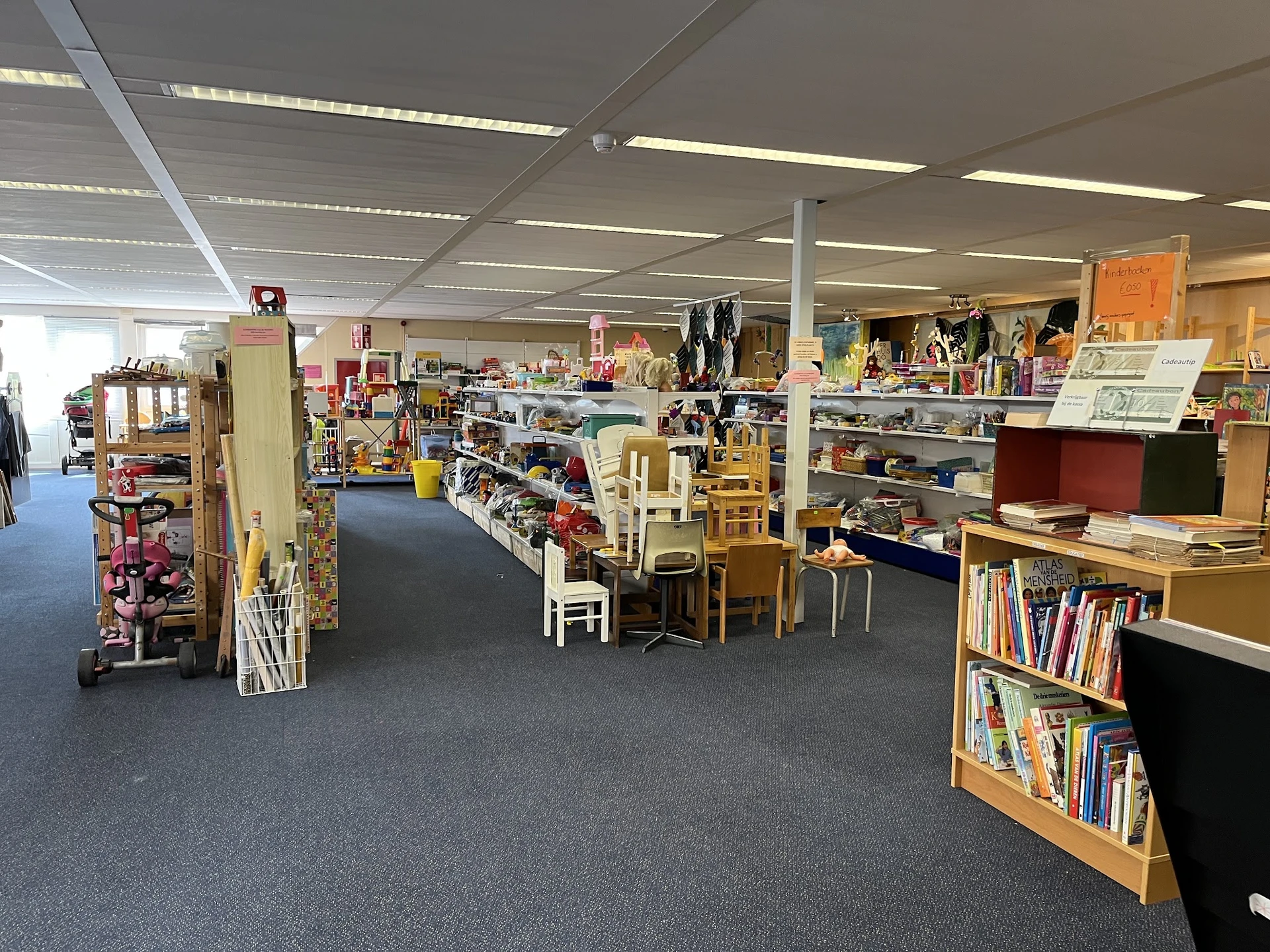 Winkelvloer van kringloopwinkel met stellingen, boeken, meubels en diverse tweedehandsartikelen